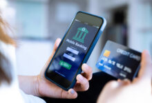 Hand holding a phone open to a mobile banking app next to a debit card