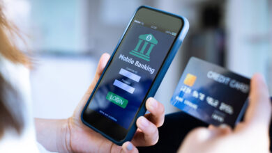 Hand holding a phone open to a mobile banking app next to a debit card