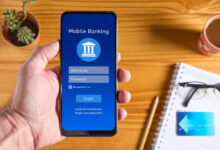 Hand holding a phone open to a mobile banking app, representing the Chime banking review