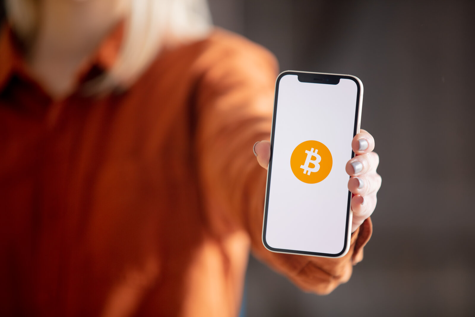 Buy Bitcoin on the Coinbase app Person holding a phone displaying a Bitcoin logo to buy cryptocurrency