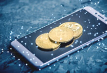 Physical Bitcoin coin resting on a smartphone showing a crypto trading app, for the Coinbase review
