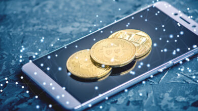 Physical Bitcoin coin resting on a smartphone showing a crypto trading app, for the Coinbase review