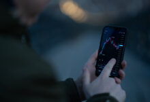 Trader monitoring stock market charts on screens while reviewing the Robinhood investing app